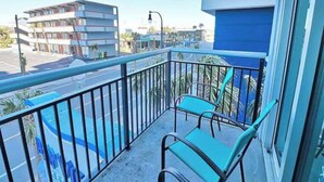 A balcony with two chairs and a view of a street with buildings and palm trees. - Oceanview Paradise at the Beach (Myrtle Beach)