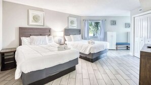 A bedroom with two beds, a bench, and a door. - Oceanview Paradise at the Beach (Myrtle Beach)