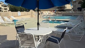 A poolside area with a blue umbrella, lounge chairs, and a pool. - Cypress Bay Getaway (Little River)