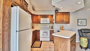 A compact kitchen with wooden cabinets, a refrigerator, an oven, and a microwave. - Cypress Bay Getaway (Little River)