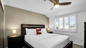 A bedroom with a bed, nightstands, a ceiling fan, and a window with blinds. - Deauville 613 (Palm Springs)