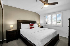 A bedroom with a bed, nightstands, a ceiling fan, and a window with blinds. - Deauville 613 (Palm Springs)
