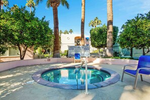 A swimming pool with a blue border, surrounded by palm trees and a building with a sign. - Deauville 613 (Palm Springs)