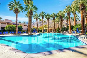 A swimming pool with palm trees, blue lounge chairs, and a mountainous backdrop. - Deauville 613 (Palm Springs)