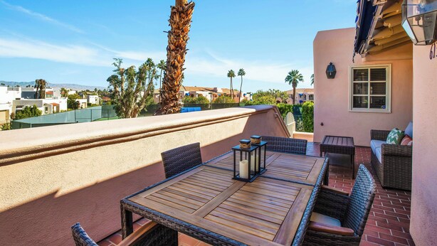 An outdoor patio with wicker furniture, a table, and a lantern. - Deauville 613 (Palm Springs)