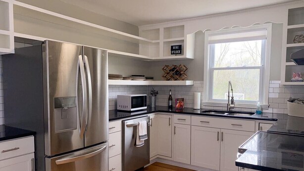 A modern kitchen with stainless steel appliances, white cabinetry, and a wooden floor. - New Listing! The Playhouse With Spa Games & More (Nashville)