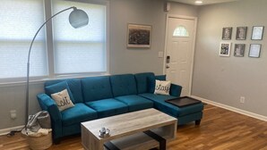 A living room with a teal sofa, a wooden coffee table, and a floor lamp. - New Listing! The Playhouse With Spa Games & More (Nashville)