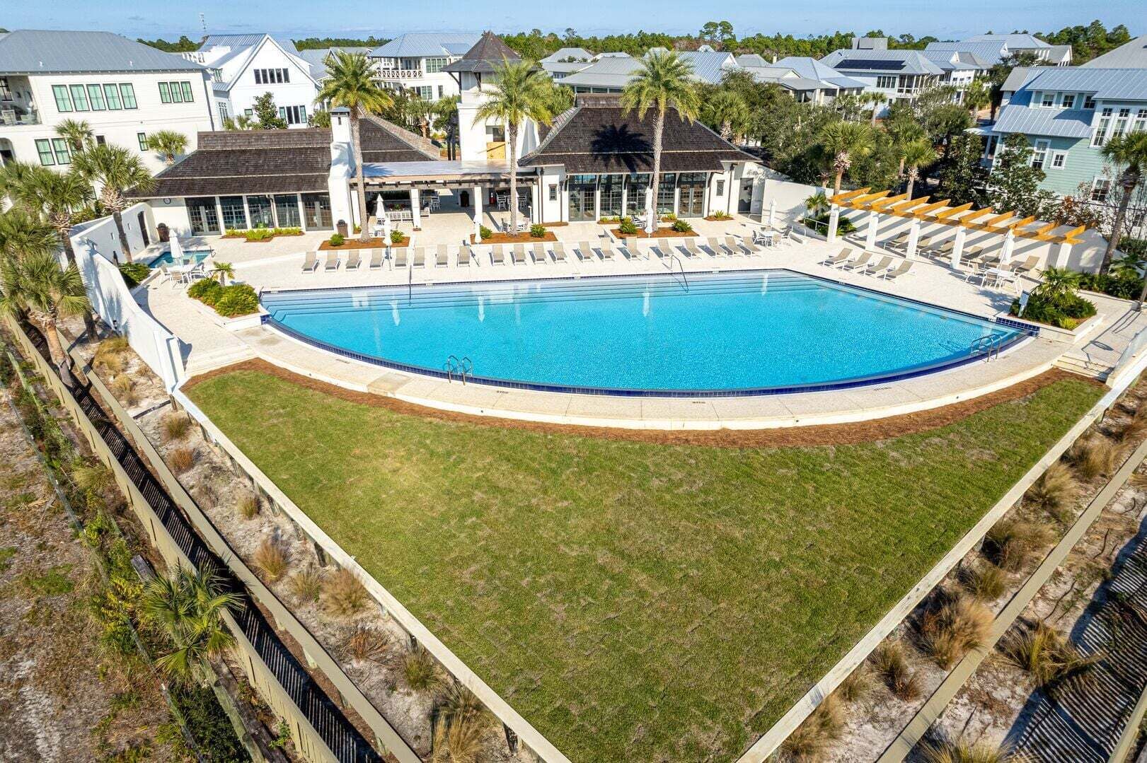 A swimming pool with a surrounding deck, a covered seating area, and a view of residential buildings in the background.