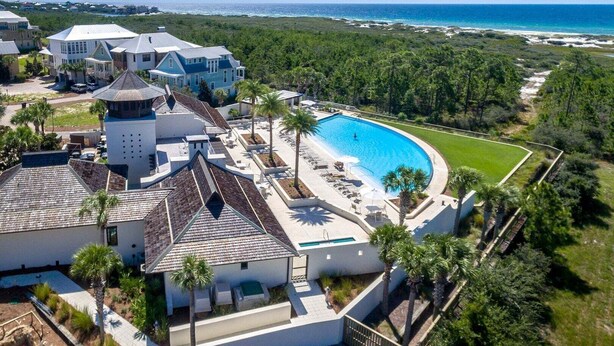 A resort with a large swimming pool, multiple buildings, and a view of the ocean. - Coastal Corner Cottage (Santa Rosa Beach)
