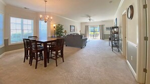 Un salon spacieux comprenant une table à manger et des chaises, un canapé gris et un ventilateur de plafond.