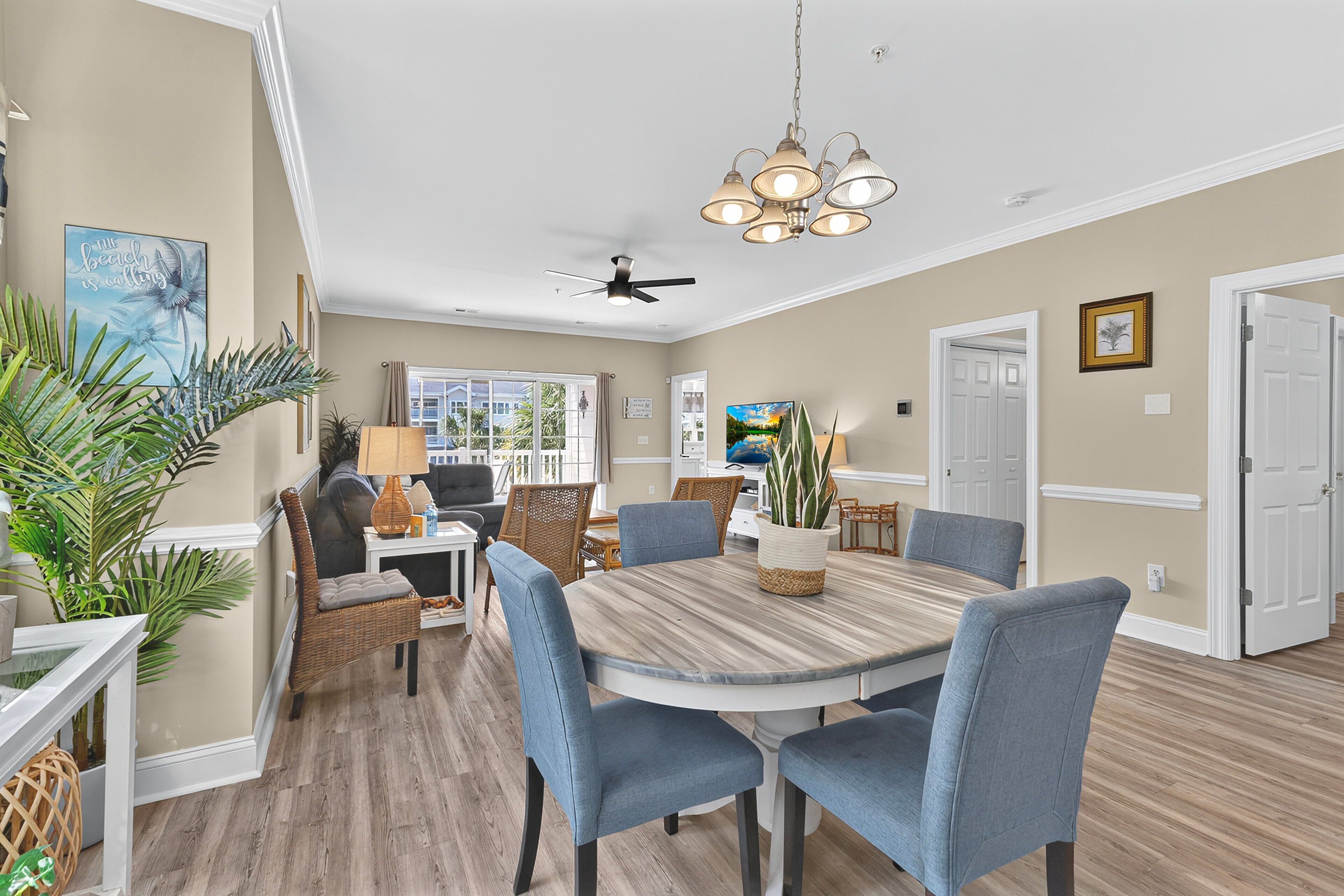 A dining area with a round table, blue chairs, and a ceiling fan.