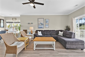 A living room with a grey sectional sofa, a wooden coffee table, wicker chairs, and a ceiling fan. - Magnolia Bovardia 4803-201 (Myrtle Beach)