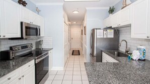 A modern kitchen with white cabinets, stainless steel appliances, and a granite countertop. - Magnolia North 4839-203 (Myrtle Beach)