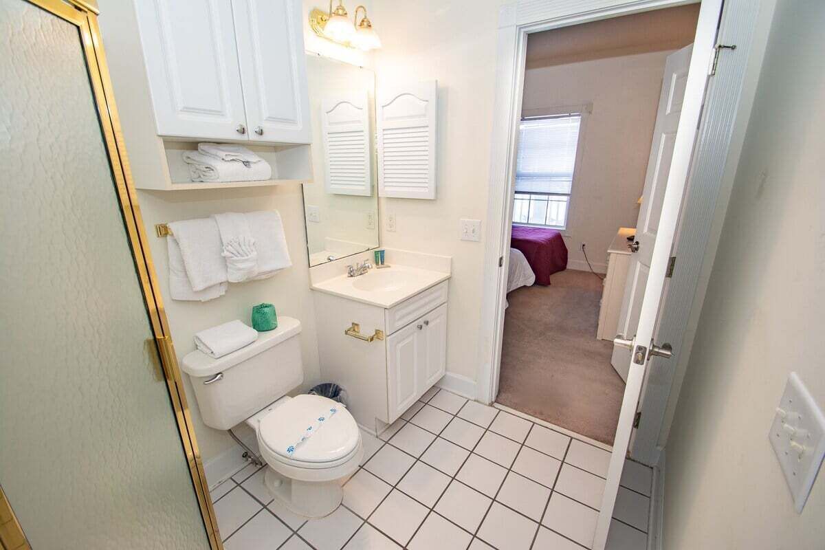 Une petite salle de bain avec des toilettes, un lavabo et des étagères où sont rangées les serviettes.