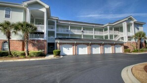 A multi-story hotel with a central courtyard, multiple balconies, and a brick facade. - Magnolia North 4827-302 (Myrtle Beach)