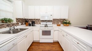 A modern kitchen with white cabinets, a microwave, stove, and a sink. - Magnolia North 4827-302 (Myrtle Beach)
