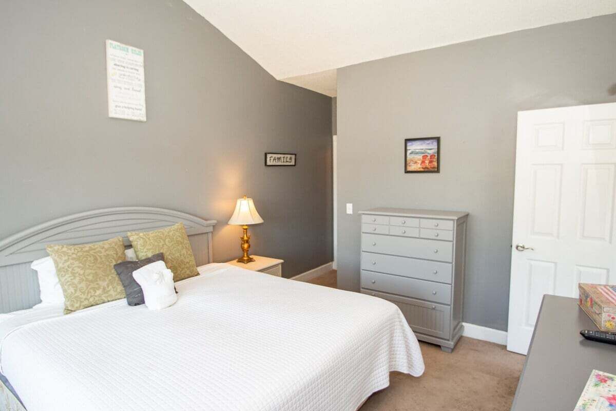 A bedroom with a bed, nightstand, dresser, and a door.