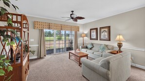 A living room with a sofa, a coffee table, a ceiling fan, and a view through a glass door to an outdoor area. - Magnolia Place 4701-104 (Myrtle Beach)