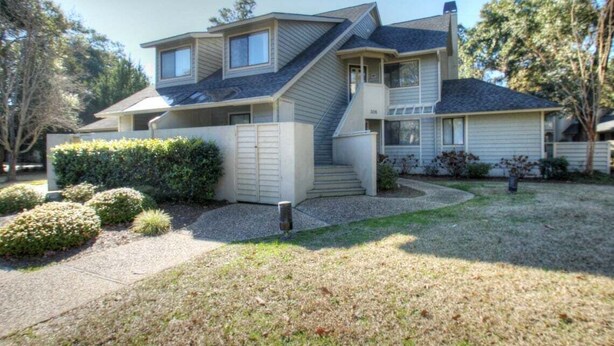 A two-story house with a front porch, a covered staircase, and a small front yard with shrubs. - West Hyde Park 2E (Myrtle Beach)