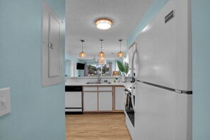 A kitchen with a white refrigerator, wooden cabinets, a dishwasher, and pendant lights. - Waterway Village 27F (Myrtle Beach)
