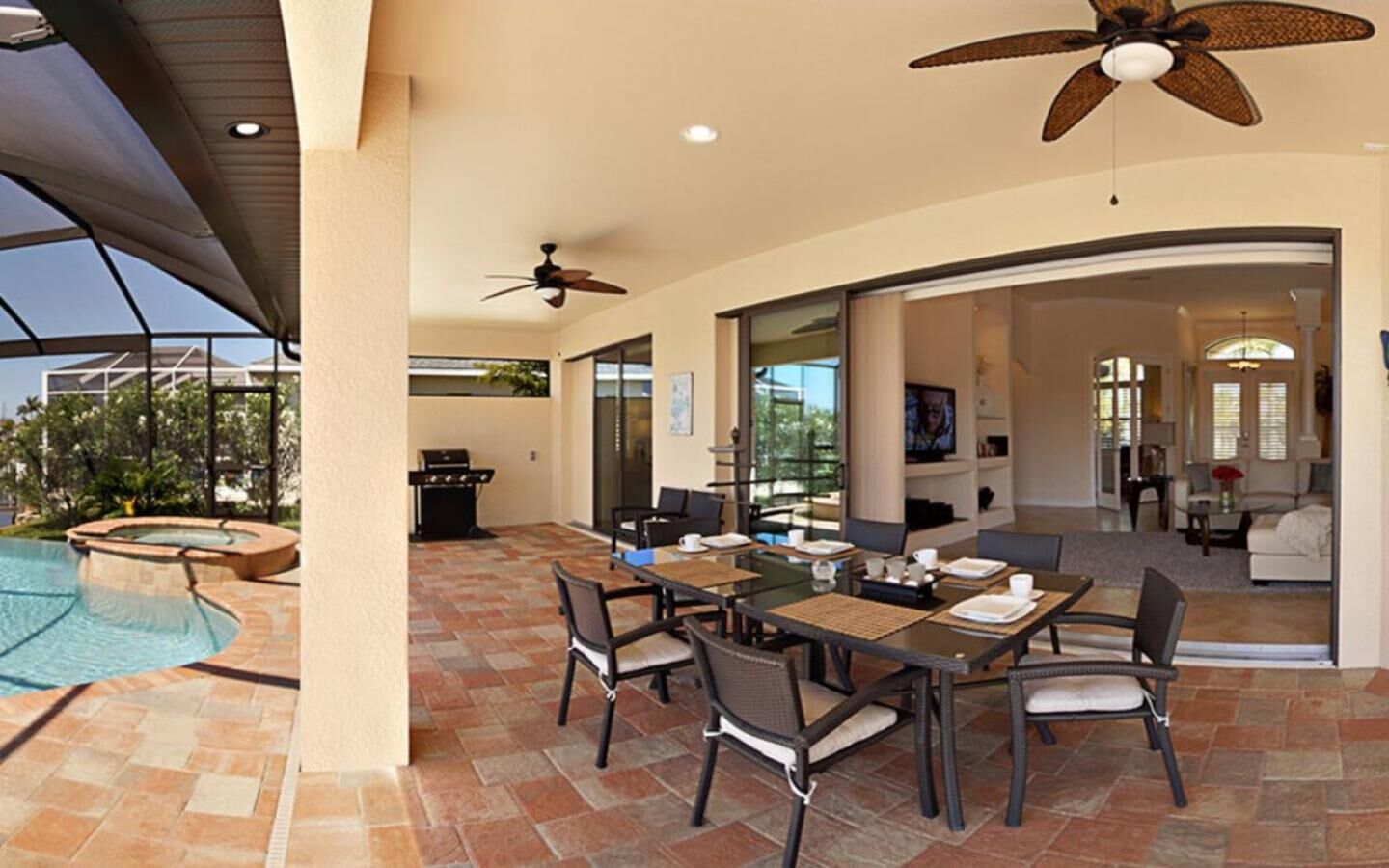 Une terrasse avec une piscine, un coin repas et un salon doté d’une cheminée.
