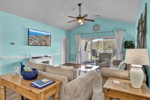 A living room with a large window, a ceiling fan, and a view of the cityscape. - Magnolia North 4879-305 (Myrtle Beach)