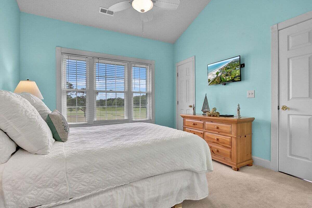 Une chambre à coucher avec un lit, une commode, une fenêtre et une porte.