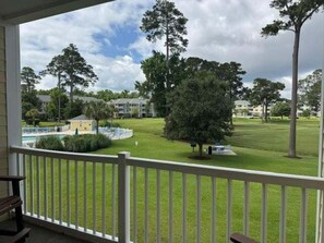 A view from a porch with a pool and a grassy area with trees. - Magnolia Pointe Luster Leaf 4890-203 (Myrtle Beach)