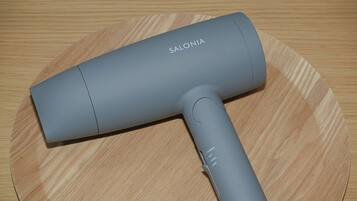 Un secador de pelo gris con el nombre de la marca 'SALONIA' sobre una superficie de madera.