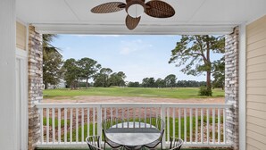 A covered porch with a table and chairs, a ceiling fan, and a view of a golf course. - Magnolia Place 4701-103 (Myrtle Beach)