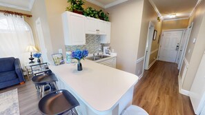 A modern kitchen with white cabinets, a central island, and a coffee maker. - Magnolia Place 4701-101 (Myrtle Beach)