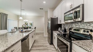 A modern kitchen with granite countertops, stainless steel appliances, and a tiled backsplash. - Peq3141 (Kissimmee)