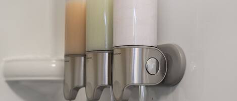 A bathroom with three soap dispensers mounted on a wall.