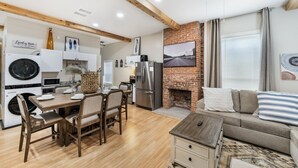 A compact living space with a kitchen area, dining table, and a sofa. - Stockyards- 4min Pet Friendly 3BR Luxe Gem (Fort Worth)