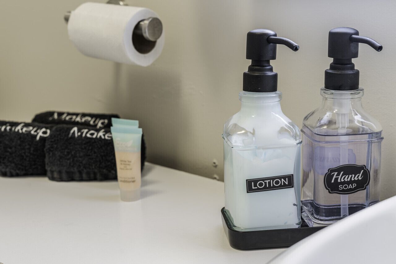 Ein Badezimmerzähler mit einer Handseifen-Spender, einer Lotionflasche und einer Toilettenpapierrolle.