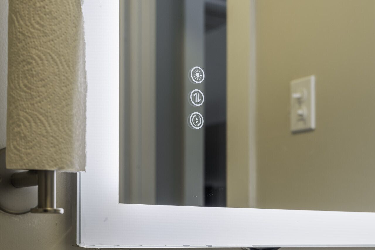 A door with a textured towel hanging on the left, a control panel with three buttons, and a light switch on the wall.
