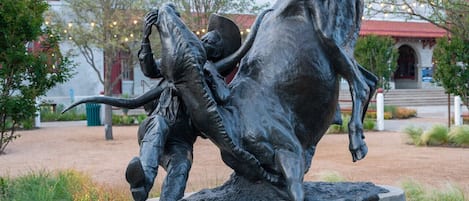 Een bronzen standbeeld van een man en een paard in een park.
