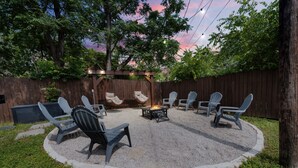 A circular outdoor seating area with a fire pit, surrounded by chairs and a wooden pergola. - Stockyards- 4min Pet Friendly 3BR Luxe Gem (Fort Worth)
