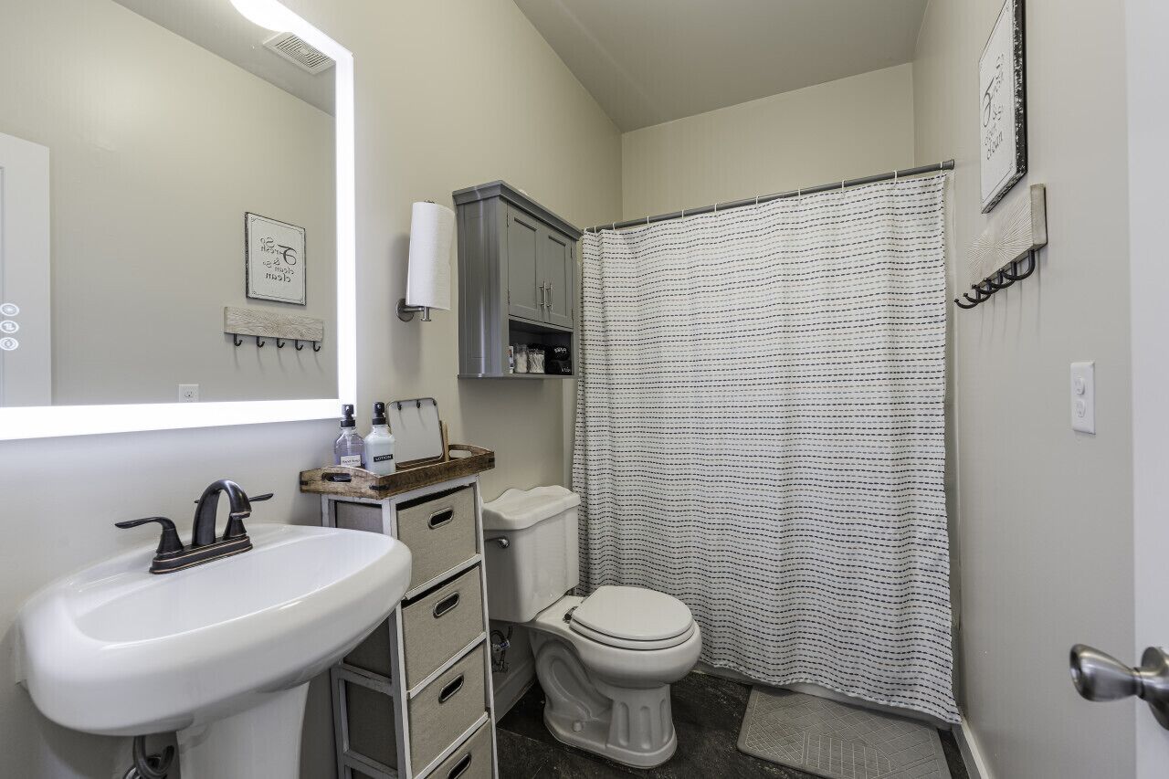 Ein Badezimmer mit weißem Waschbecken, Toilette, Duschvorhang und Spiegel.