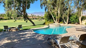 A swimming pool with lounge chairs and a view of a golf course and mountains. - Villa Bella (Rancho Mirage)