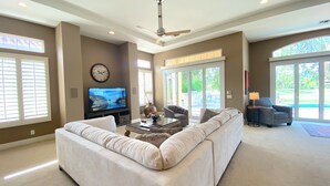 A living room with a sectional sofa, a flat-screen TV, and a ceiling fan. - Villa Bella (Rancho Mirage)
