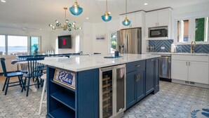 A modern kitchen with a central island, white cabinetry, and blue accents.