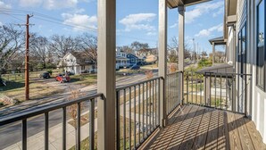 Eine Veranda mit Blick auf eine Straße, Häuser und einen klaren Himmel.