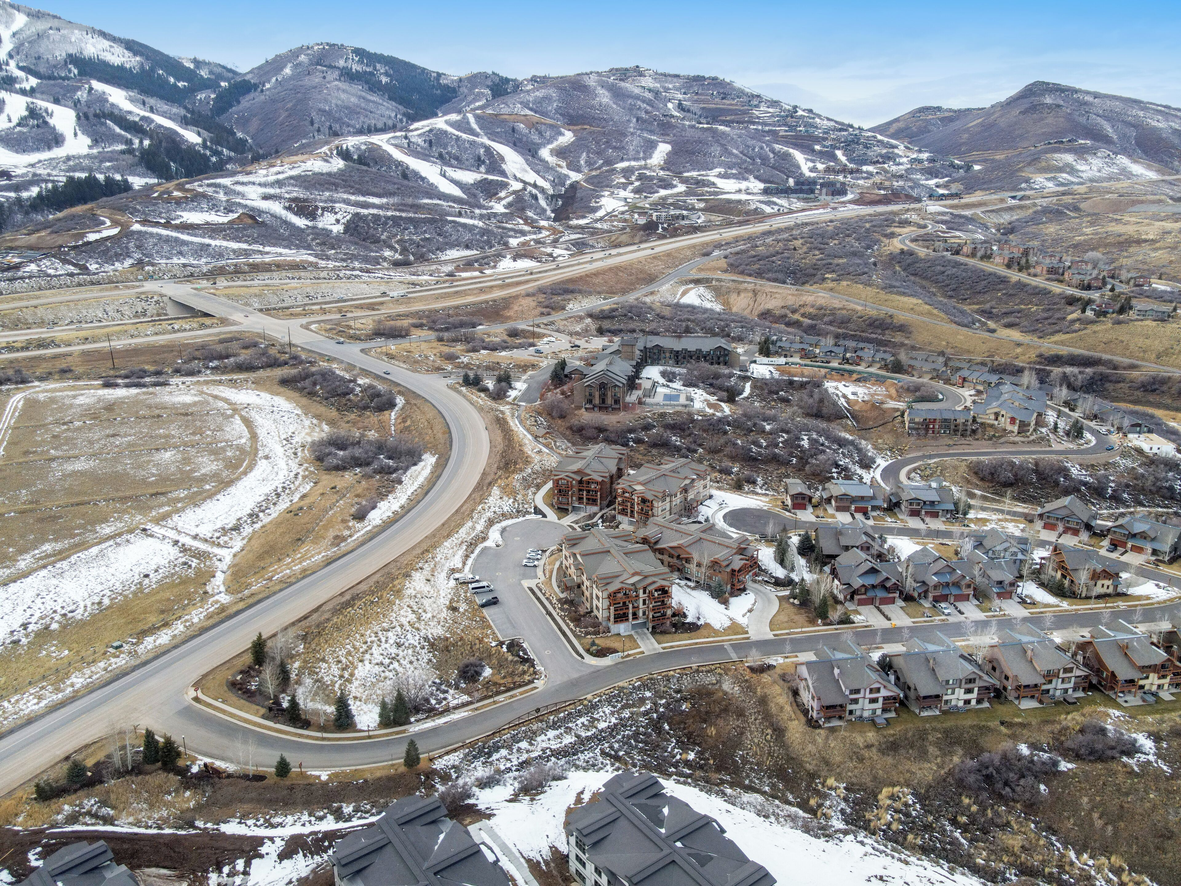 A residential area with a winding road, houses, and a mountainous backdrop.