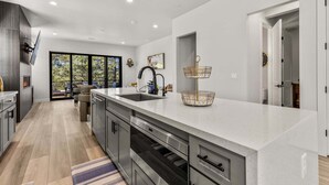 Una cucina moderna con una grande isola, elettrodomestici integrati e vista sull'esterno.