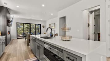 A modern kitchen with a large island, built-in appliances, and a view to the outdoors.