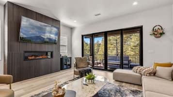 A modern living room with a fireplace, a large window, and a cozy seating area.
