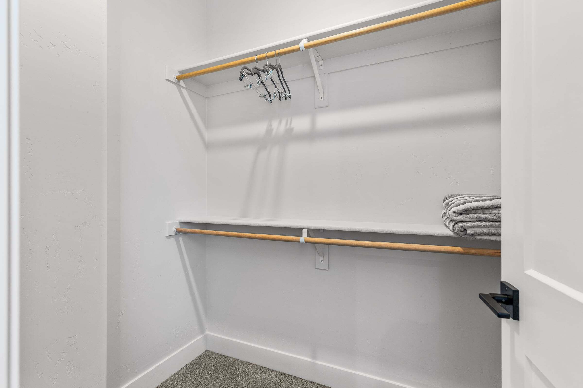 Ein Eckschrank mit zwei Holzböden, einem Handtuchhalter und einer Tür mit schwarzem Griff.