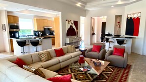 A modern living room with a sofa, armchairs, and a coffee table. There is a kitchen area with a dining table and chairs. - Double Eagle (Rancho Mirage)