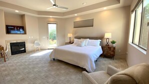 A bedroom with a bed, a TV, a fireplace, and a window. - Double Eagle (Rancho Mirage)
